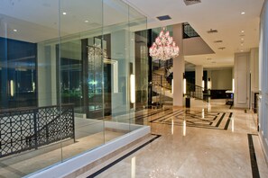 A modern hotel lobby with a glass partition, a chandelier, and a marble floor. - Samala Hotel Jakarta Cengkareng (Jakarta)