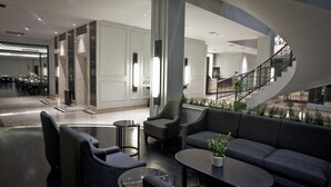 Een moderne hotellobby met een gebogen trap, een zithoek en een eetgedeelte.