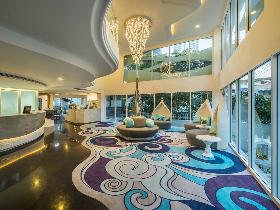 Eine moderne Lobby mit einer Rezeption, einer Sitzecke und großen Fenstern mit Blick ins Freie.