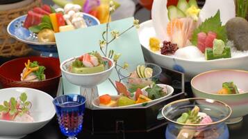 A variety of dishes arranged on a table, including sushi, sashimi, and other appetizers.