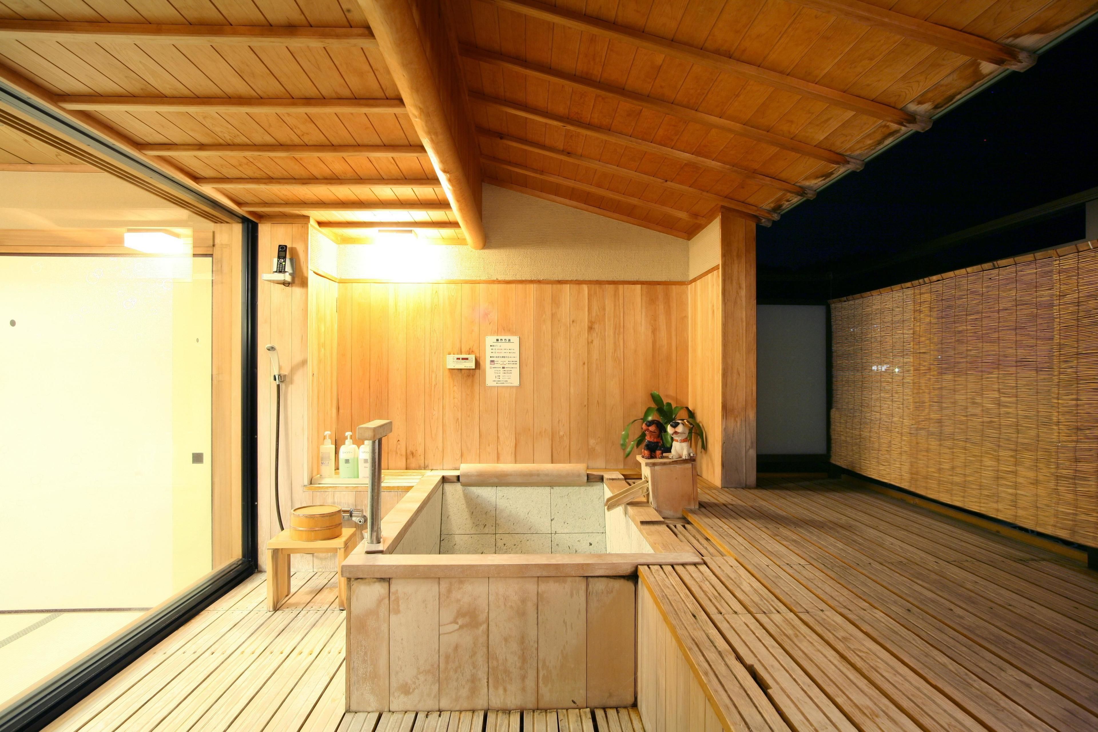 A wooden sauna with a large hot tub, wooden flooring, and a bamboo wall.