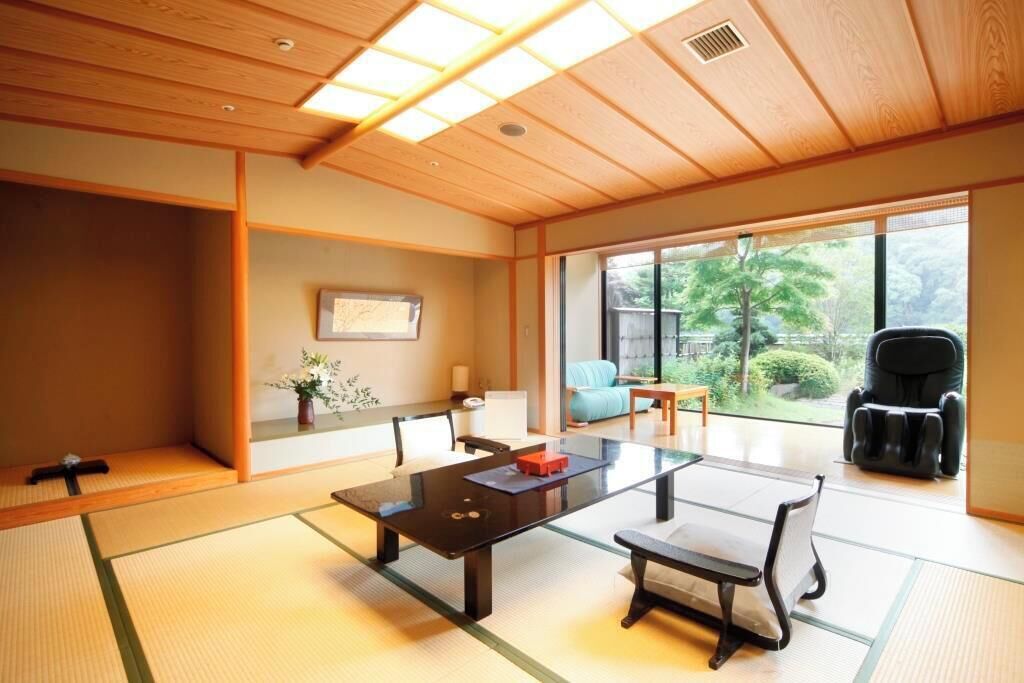 Una habitación tradicional japonesa con suelo de tatami, una mesa baja y una silla.