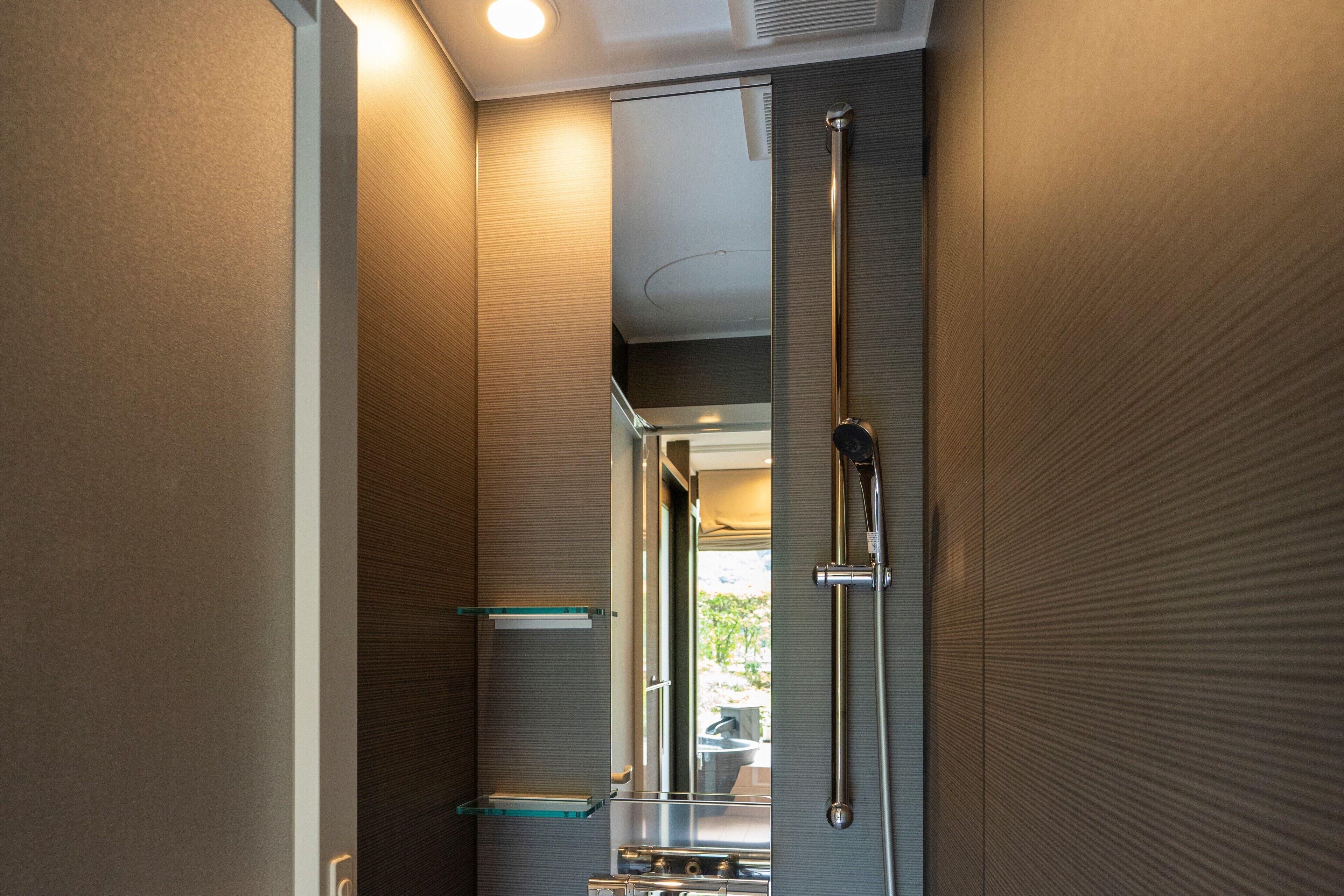 A modern bathroom with a glass shower enclosure, a mirror, and a towel rack.