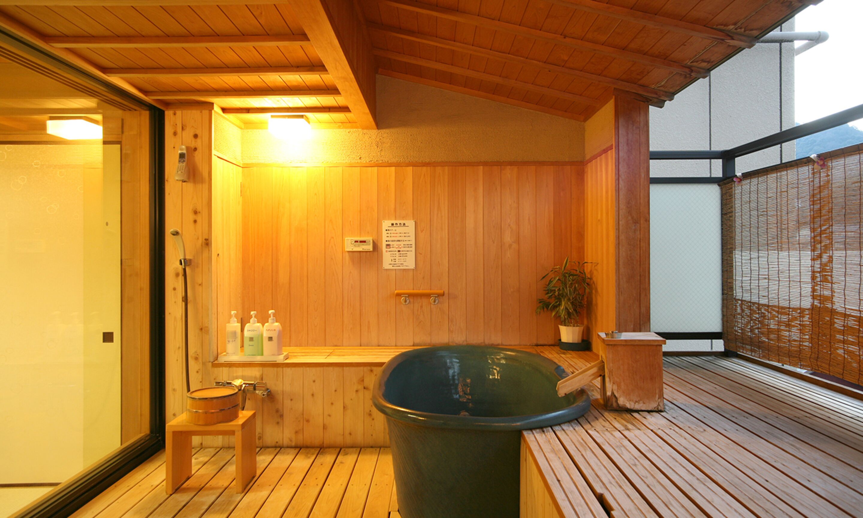 Una sauna de madera con un banco, un balde grande y una planta en maceta.