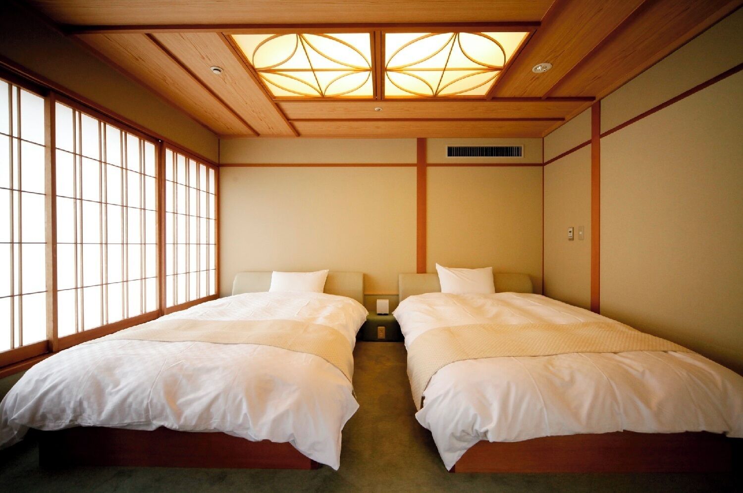 A hotel room with two beds, a large window with a view, and a traditional Japanese-style ceiling.