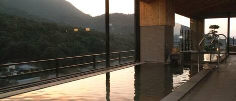 A modern indoor swimming pool with a view of a forested hillside.