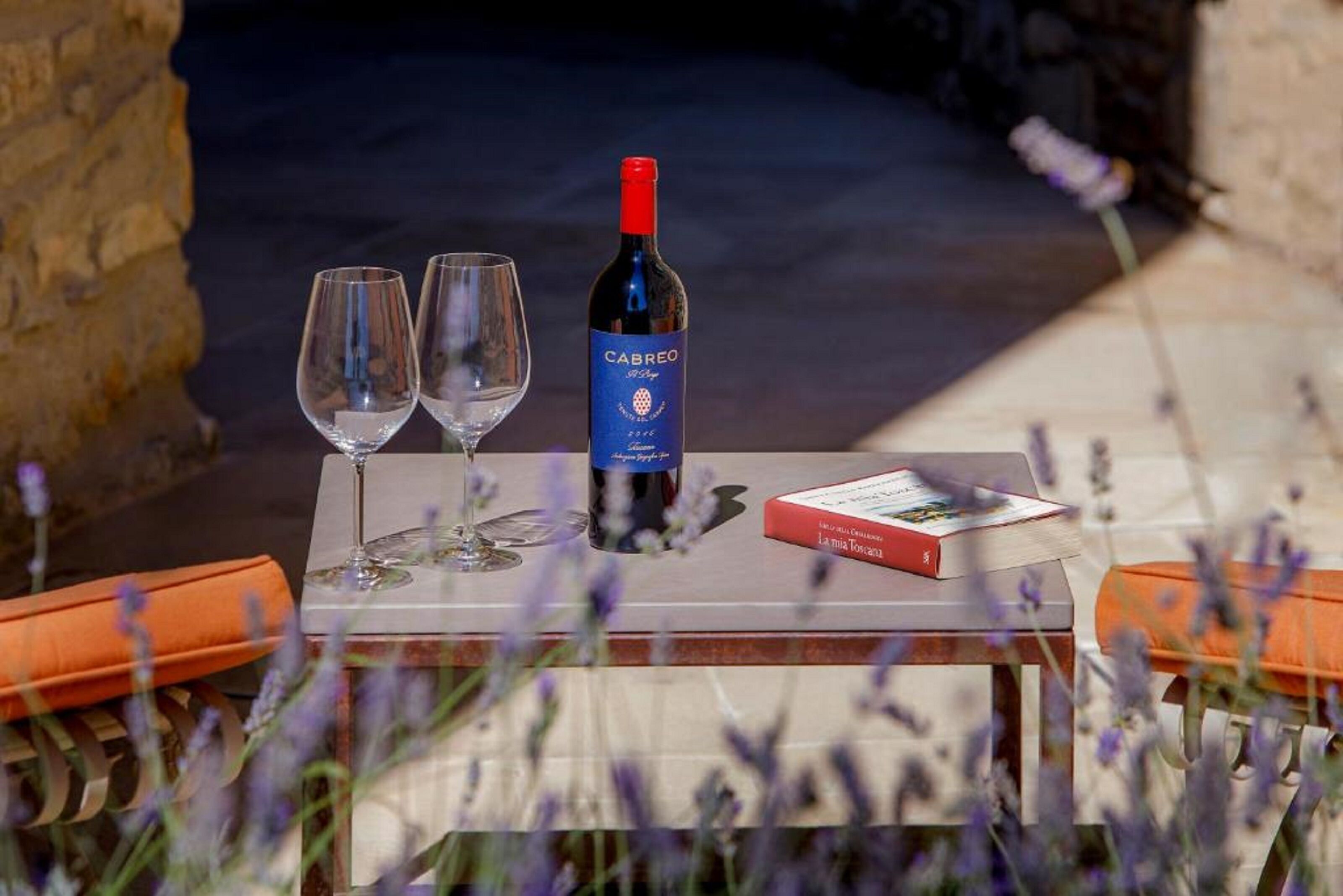 Una mesa con una botella de vino Cabreo, dos copas vacías y un libro titulado 'La Mia Toscana'.