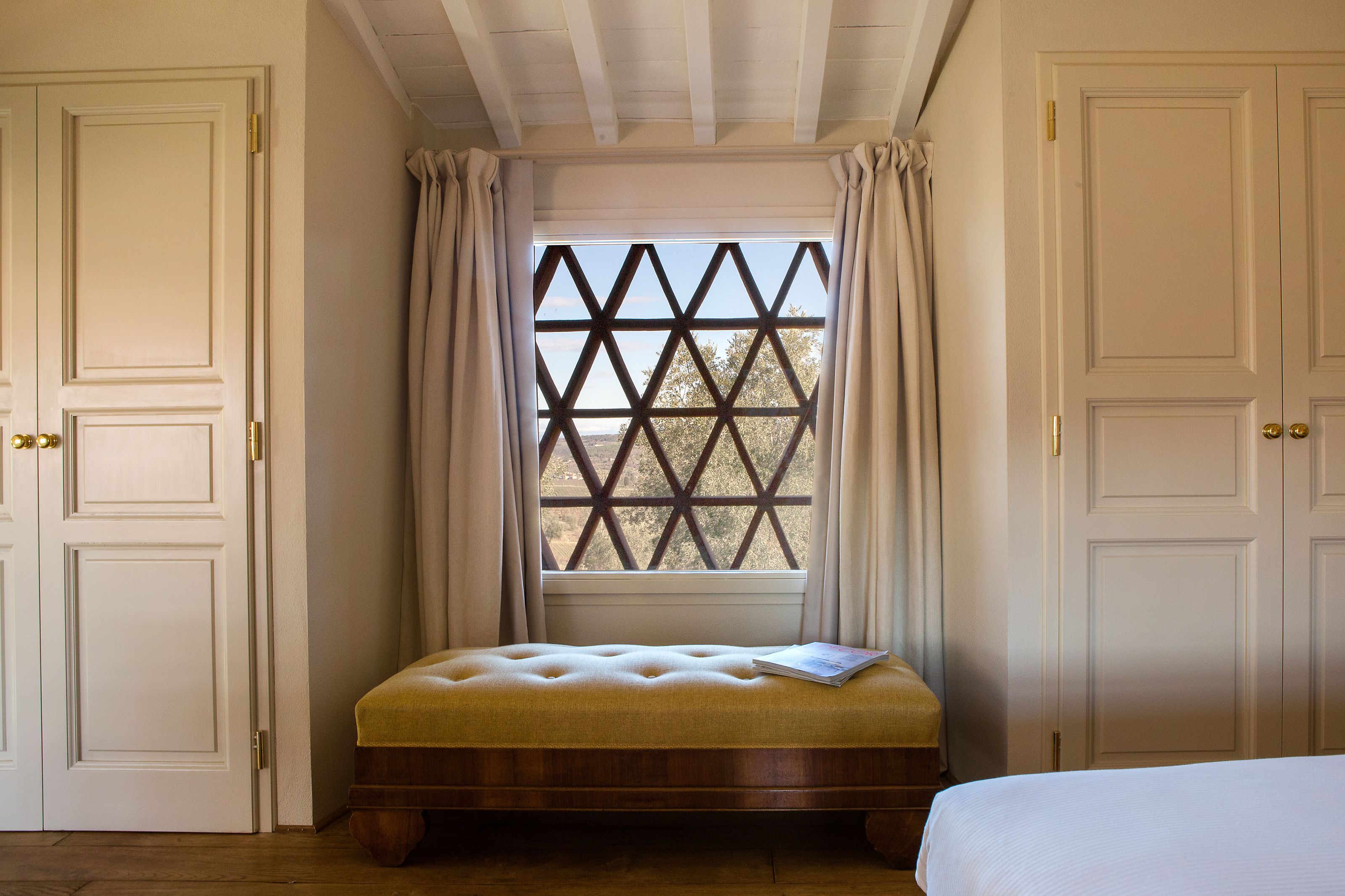 A bedroom with a wooden bed, a window with a lattice design, and white doors.