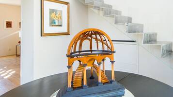 Een model van een houten gazebo op een tafel, een trap en een lijst met een foto aan de muur.