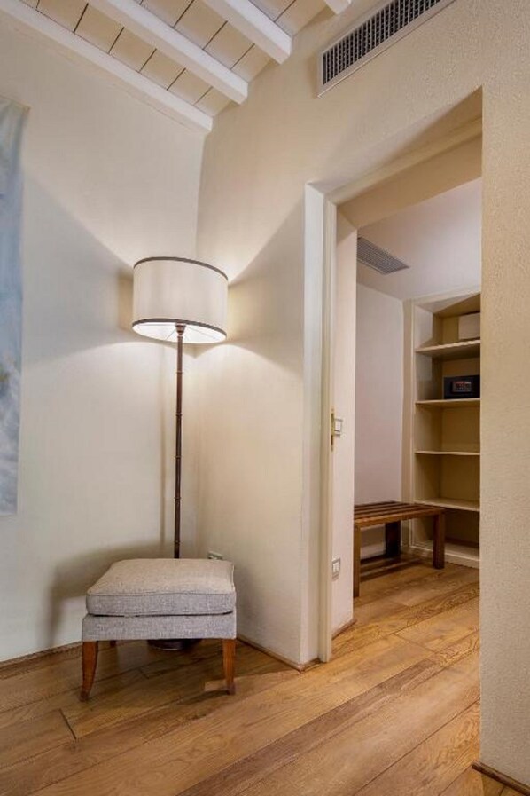 A corner room with a floor lamp, a bench, and a shelving unit.