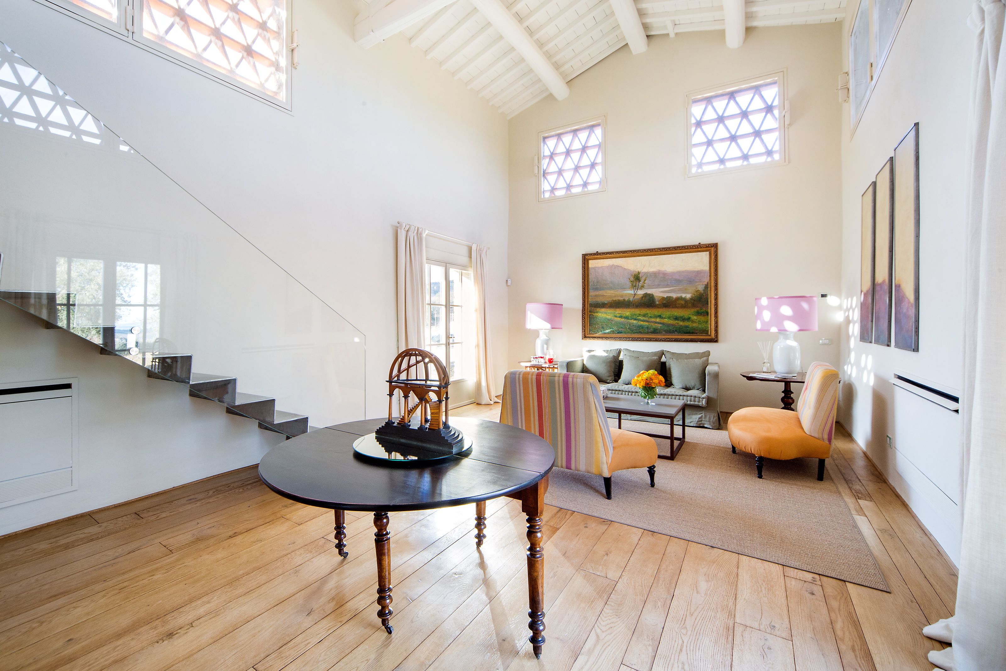A spacious living area with a staircase, a round table, and a sofa.