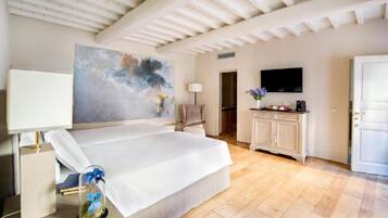 A bedroom with a large bed, a painting on the wall, a television, and a cabinet with a vase of flowers.