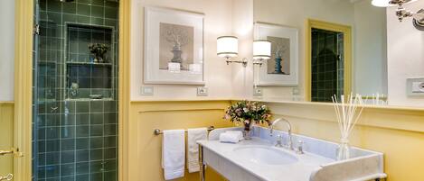 A bathroom with a wooden floor, a white sink with a mirror above it, and a shower with a glass door.