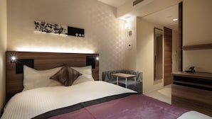 Una habitación de hotel moderna con una cama grande, una mesita de noche, un escritorio pequeño y un espejo.
