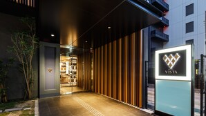Una entrada de hotel moderna con fachada de vidrio, pared de paneles de madera y un letrero que dice "HOTEL VISTA".