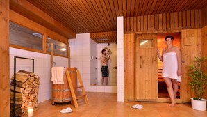 Een houten interieur met een sauna, een houten bank en een stapel hout.