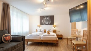 Een hotelkamer met een bed, een bank, een klein tafeltje, een stoel en een televisie.