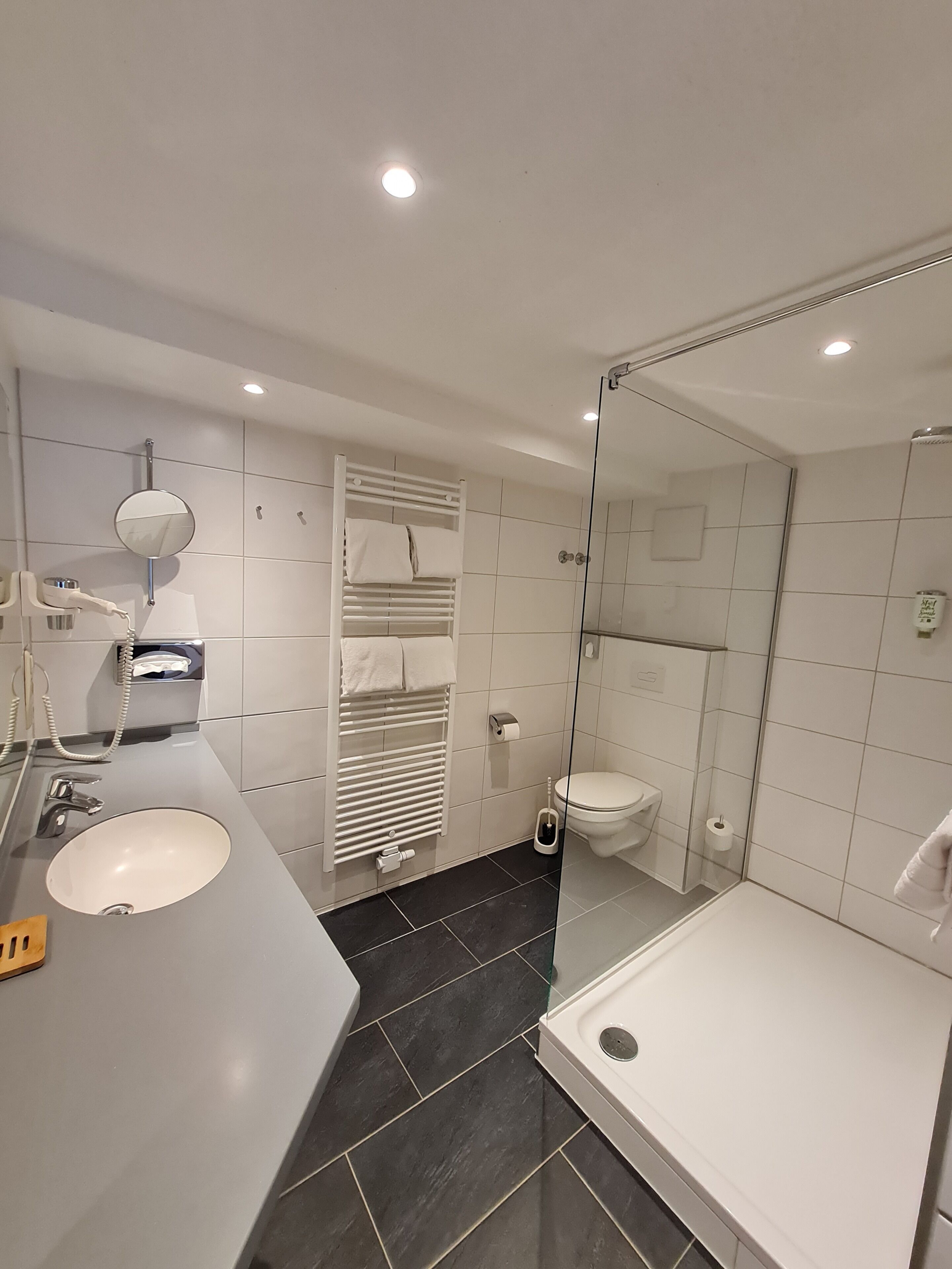 Un baño moderno con lavamanos, inodoro y ducha.