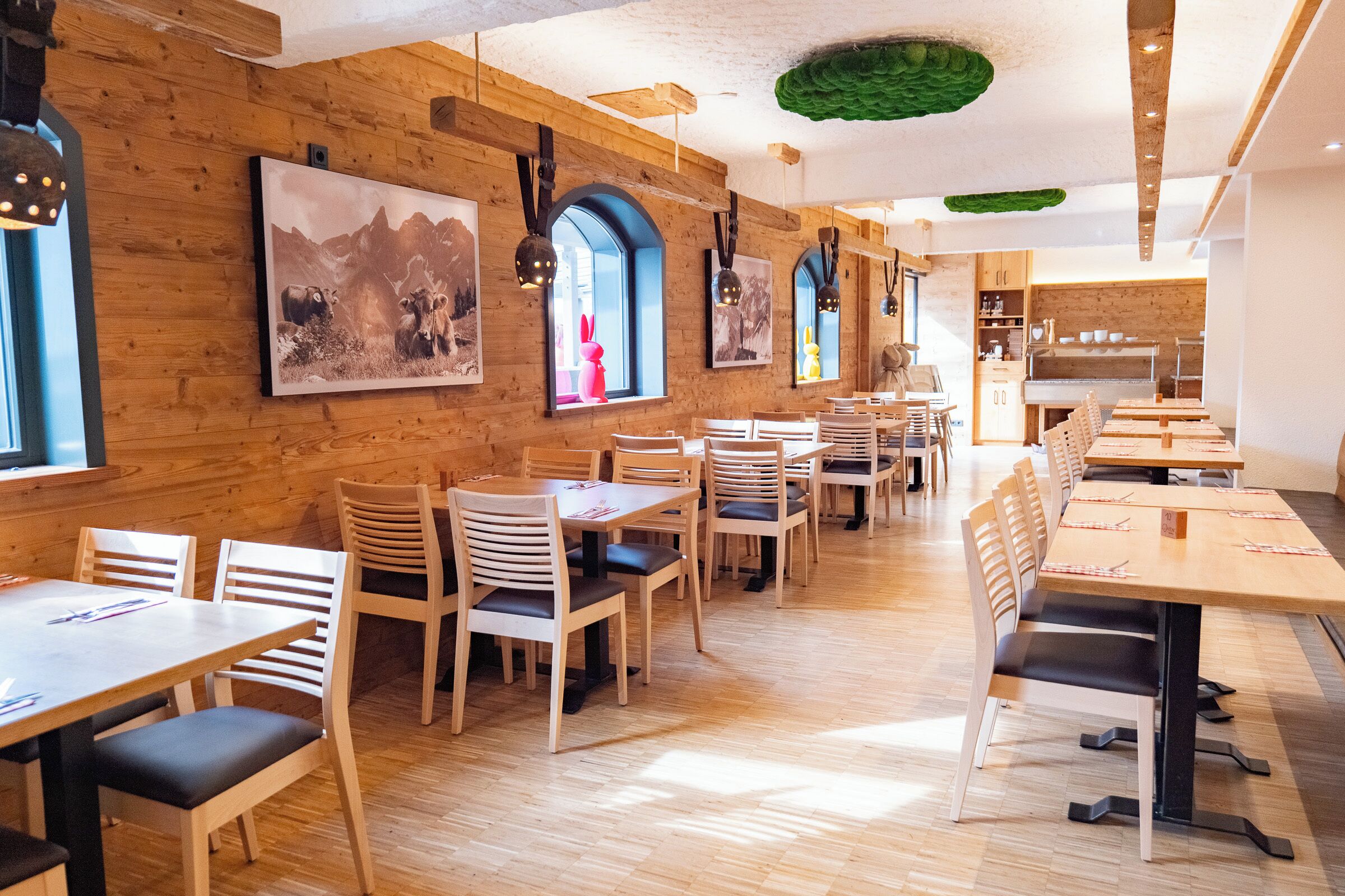 Un restaurant aux murs en bois, doté de nombreuses tables et chaises, et dont les murs sont ornés d’œuvres d’art.