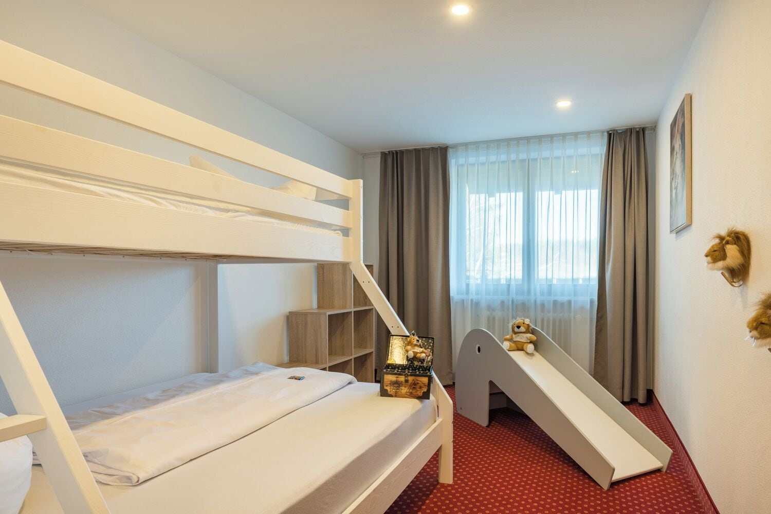 A bunk bed room with a small desk and a slide.