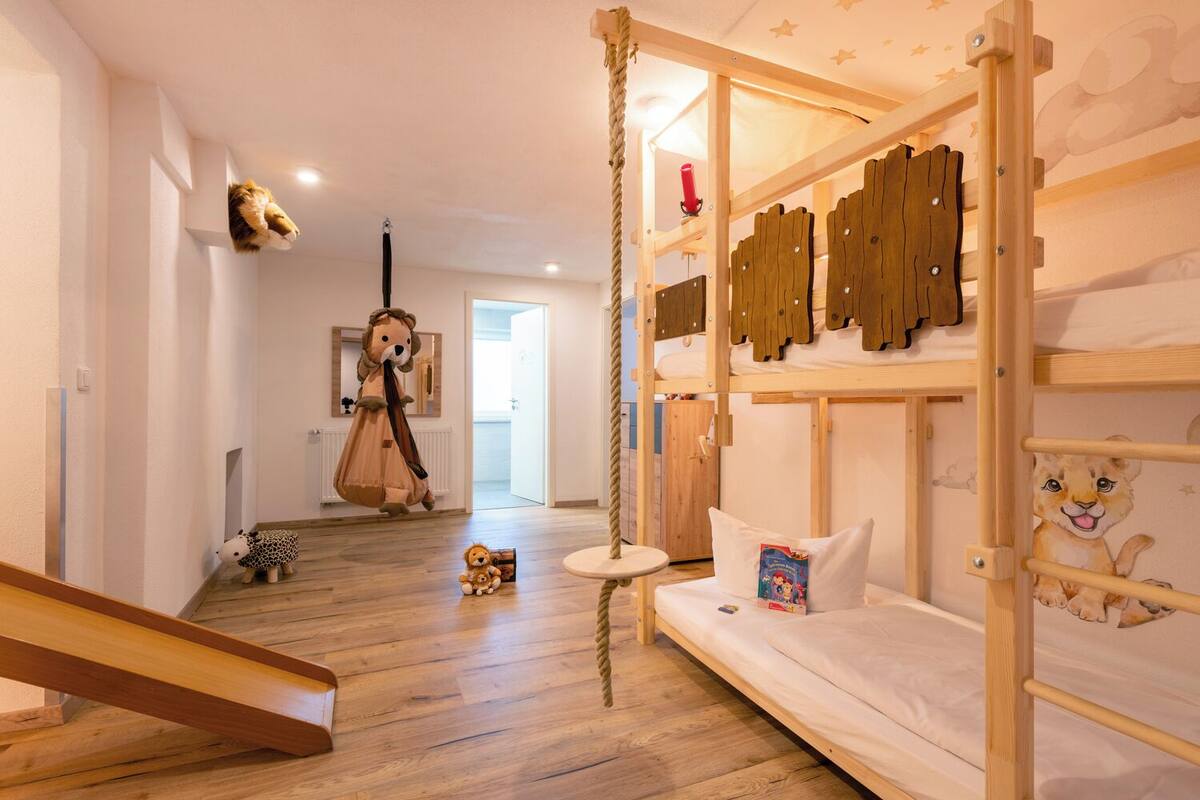 Une chambre d’enfant avec des lits superposés, un jouet suspendu et un espace de jeux.