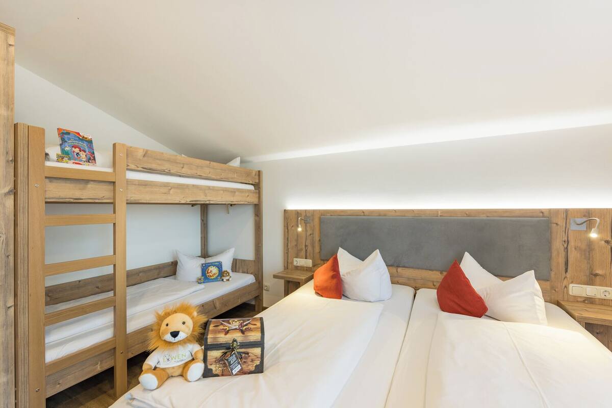 Une chambre avec un lit superposé, un doudou en forme de lion et un coffre au trésor.