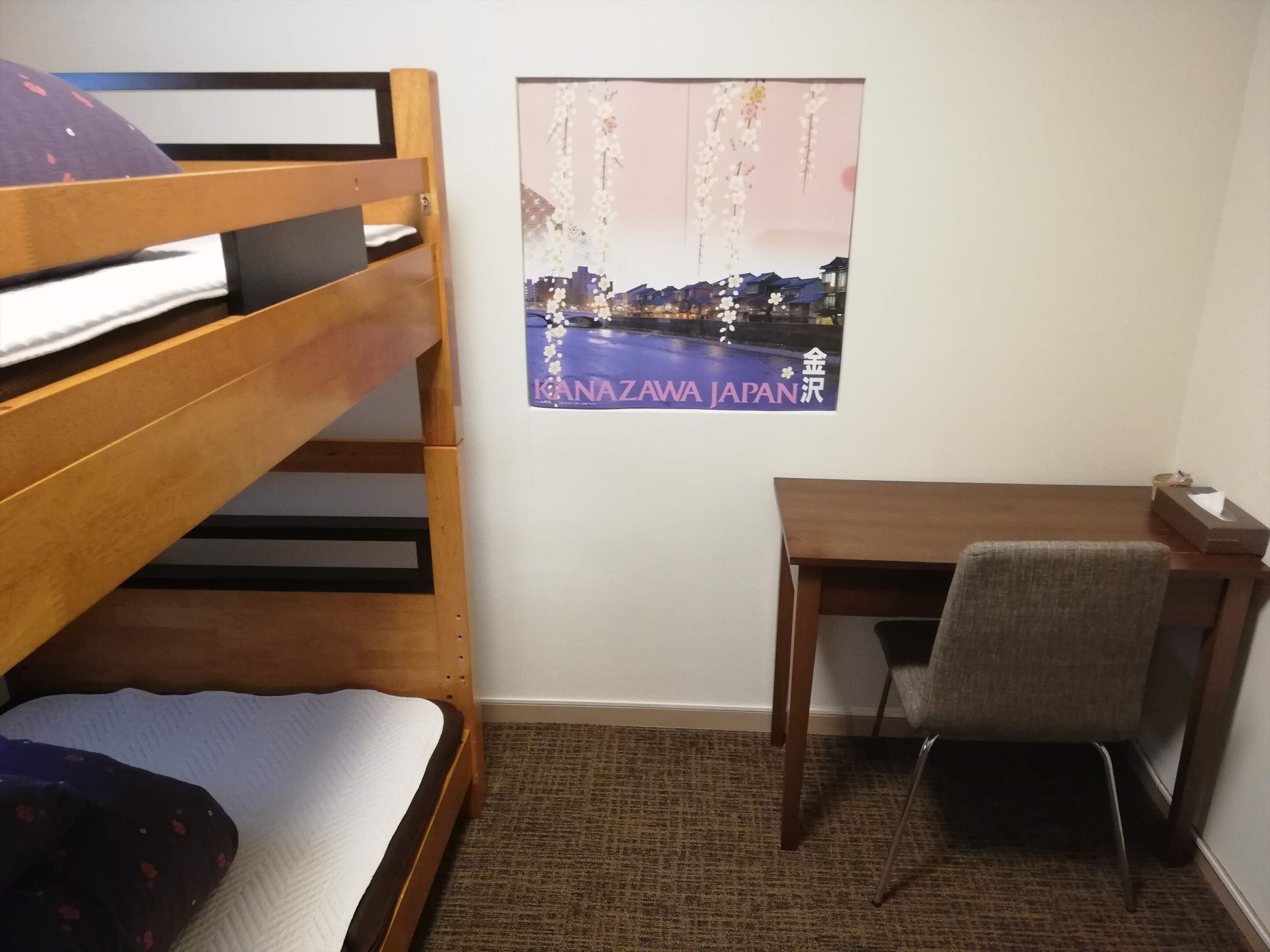 A bunk bed with a pillow and a small desk with a chair.
