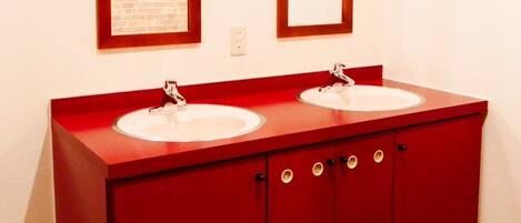 A red bathroom vanity with two sinks and a mirror above each.