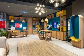 Eine moderne Hotelhalle mit Empfangsbereich, Bar und Sitzgelegenheiten.