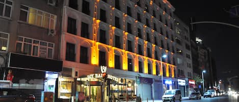 A hotel with a classic architectural style, featuring a prominent entrance with a glass facade and a signboard.