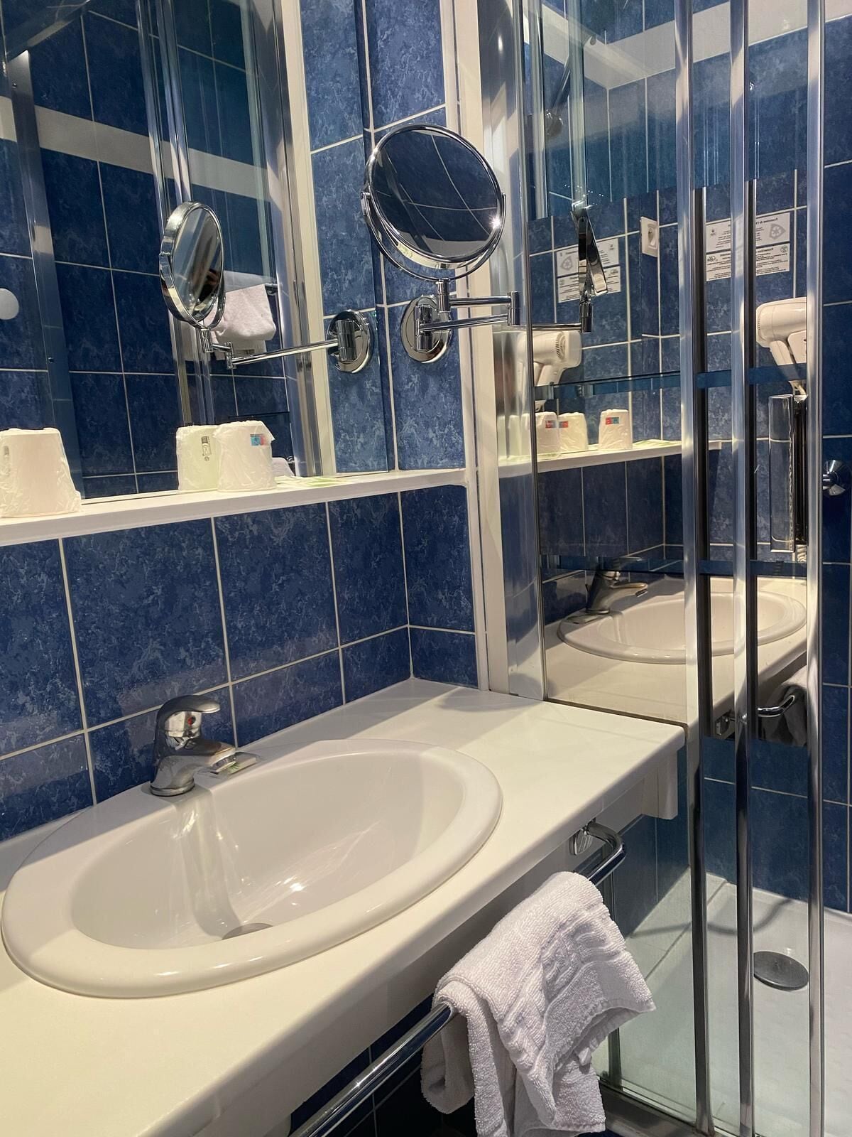 Een badkamer met een witte wastafel, een spiegel en een douchecabine met glazen wanden.