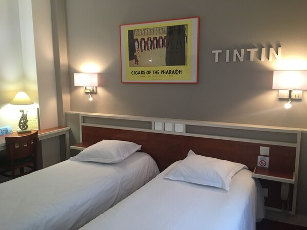 Una habitación de hotel con dos camas, un cartel enmarcado en la pared y dos lámparas de pared.