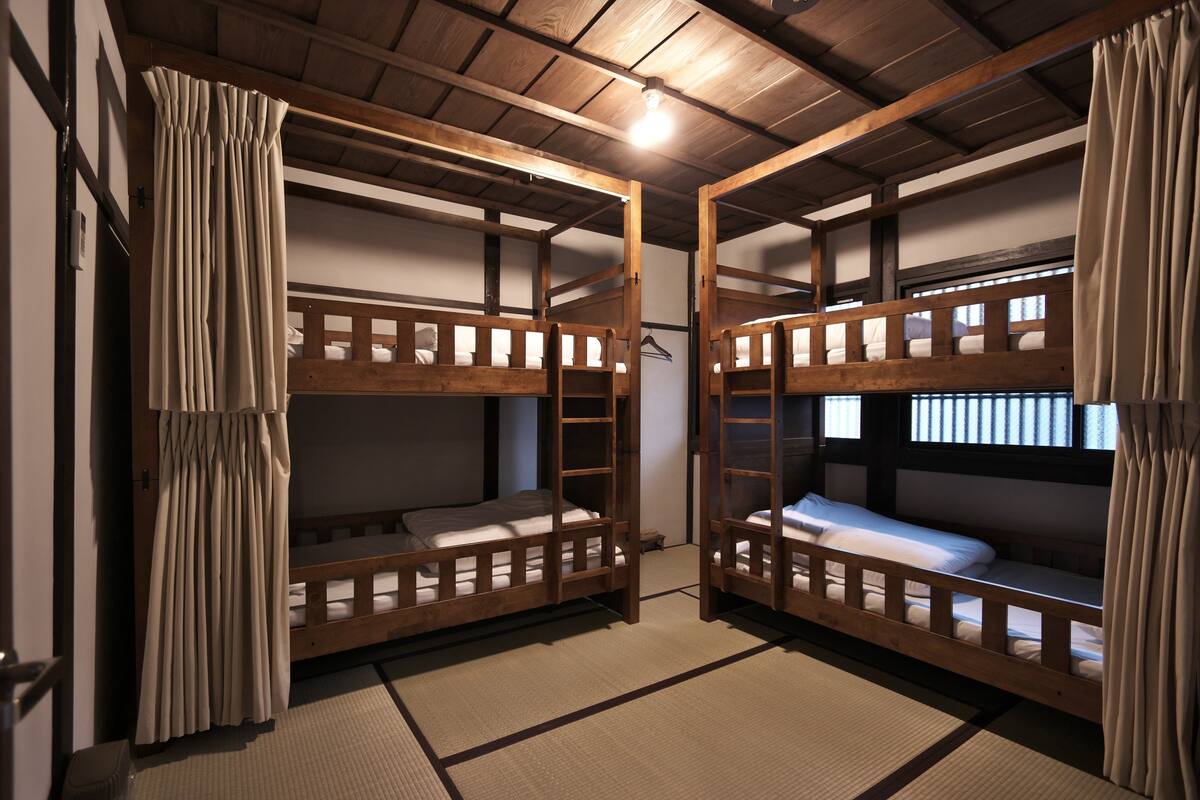 A traditional Japanese-style room with tatami flooring, wooden bunk beds, and sliding doors.