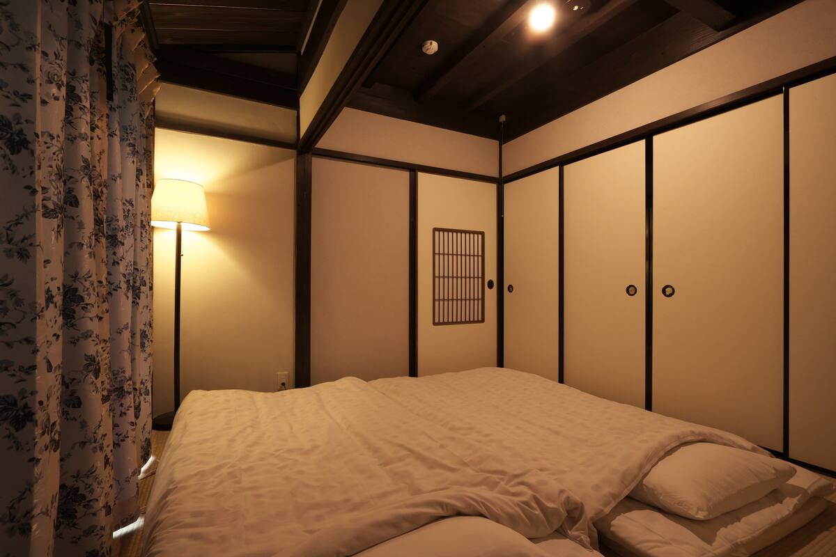 A bedroom with a bed, a nightstand, a lamp, and a wardrobe.
