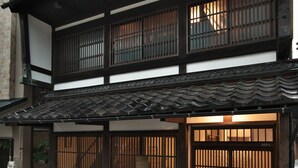 Perinteinen japanilainen rakennus, jossa on tiilikatto, puuristikkoikkunat ja soralla päällystetty polku.