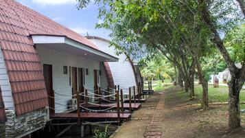 A row of white buildings with red roofs, wooden decks, and a paved path.