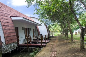 A row of white buildings with red roofs, wooden decks, and a paved path. - Kanaka Lake Villa (Batam)