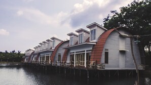 A row of waterfront cottages with a red roof, wooden deck, and a calm lake. - Kanaka Lake Villa (Batam)