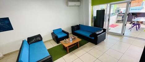 Une pièce avec deux canapés bleus, une table basse en bois et un tapis vert.