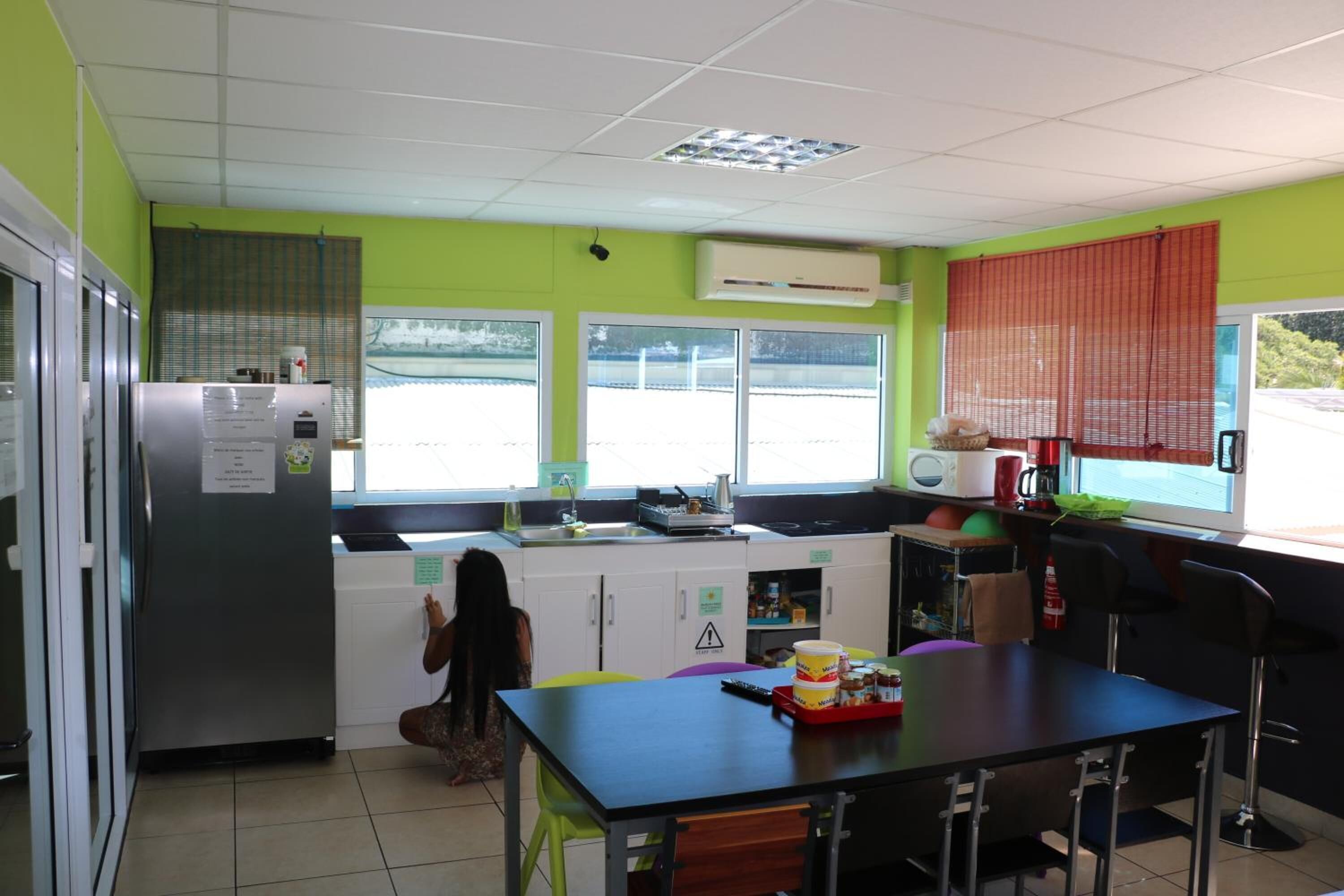 Cocina equipada con refrigerador, microondas y pileta. Se observa una ventana con persianas y vista al exterior.