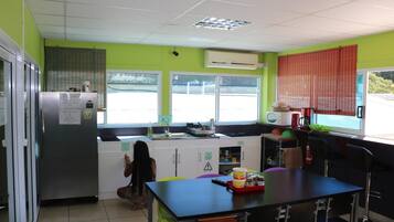 Cocina equipada con refrigerador, microondas y pileta. Se observa una ventana con persianas y vista al exterior.