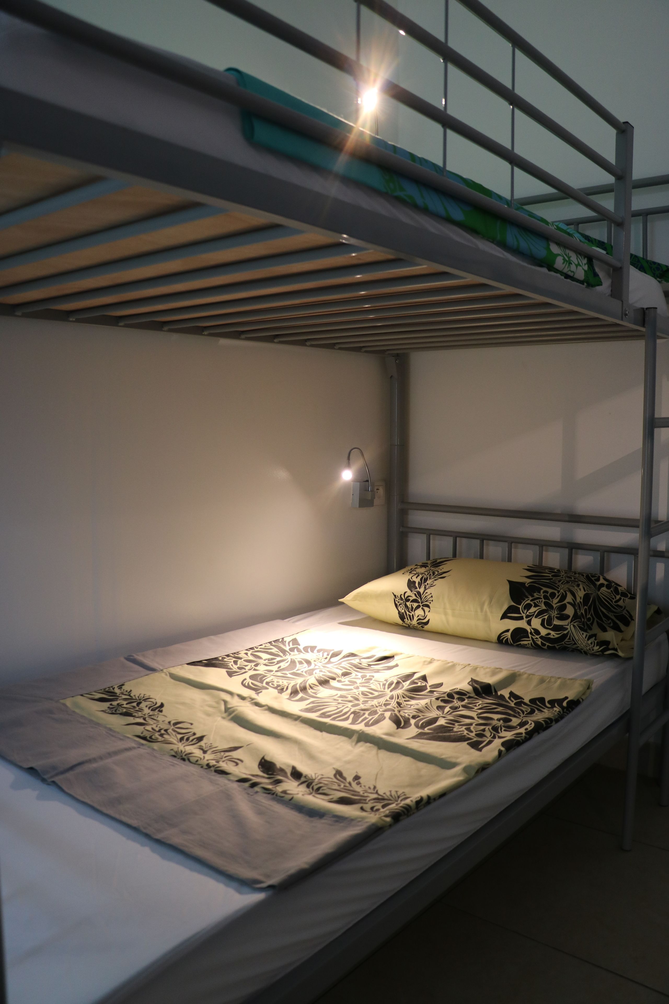 Ein Stockbett mit einem Bett unten und einem Kopfteil inklusive Leuchte.