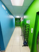 A hallway with green and blue walls, a sign that says "Hello! Adventure Awaits", and a rack with shoes.