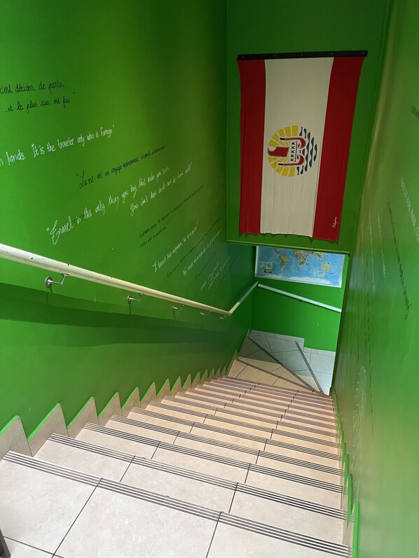 Una escalera verde con barandilla y una pared con citas motivacionales.