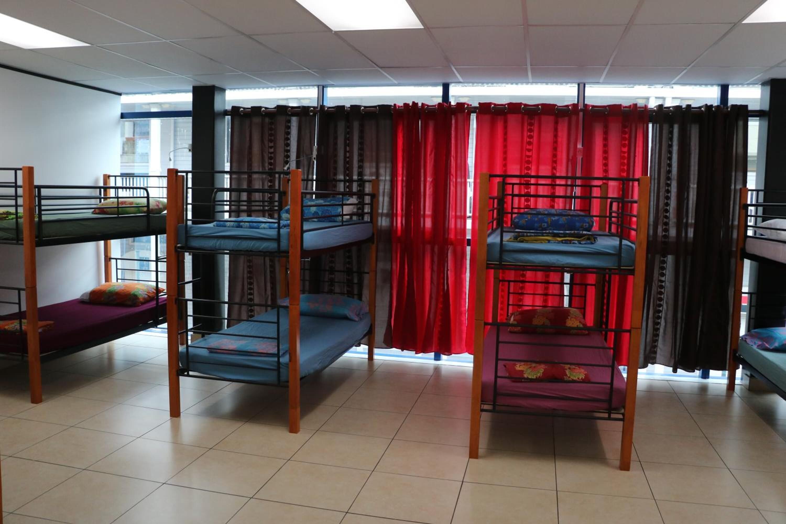 Un dormitorio con literas, una ventana con cortinas y suelo de baldosas.