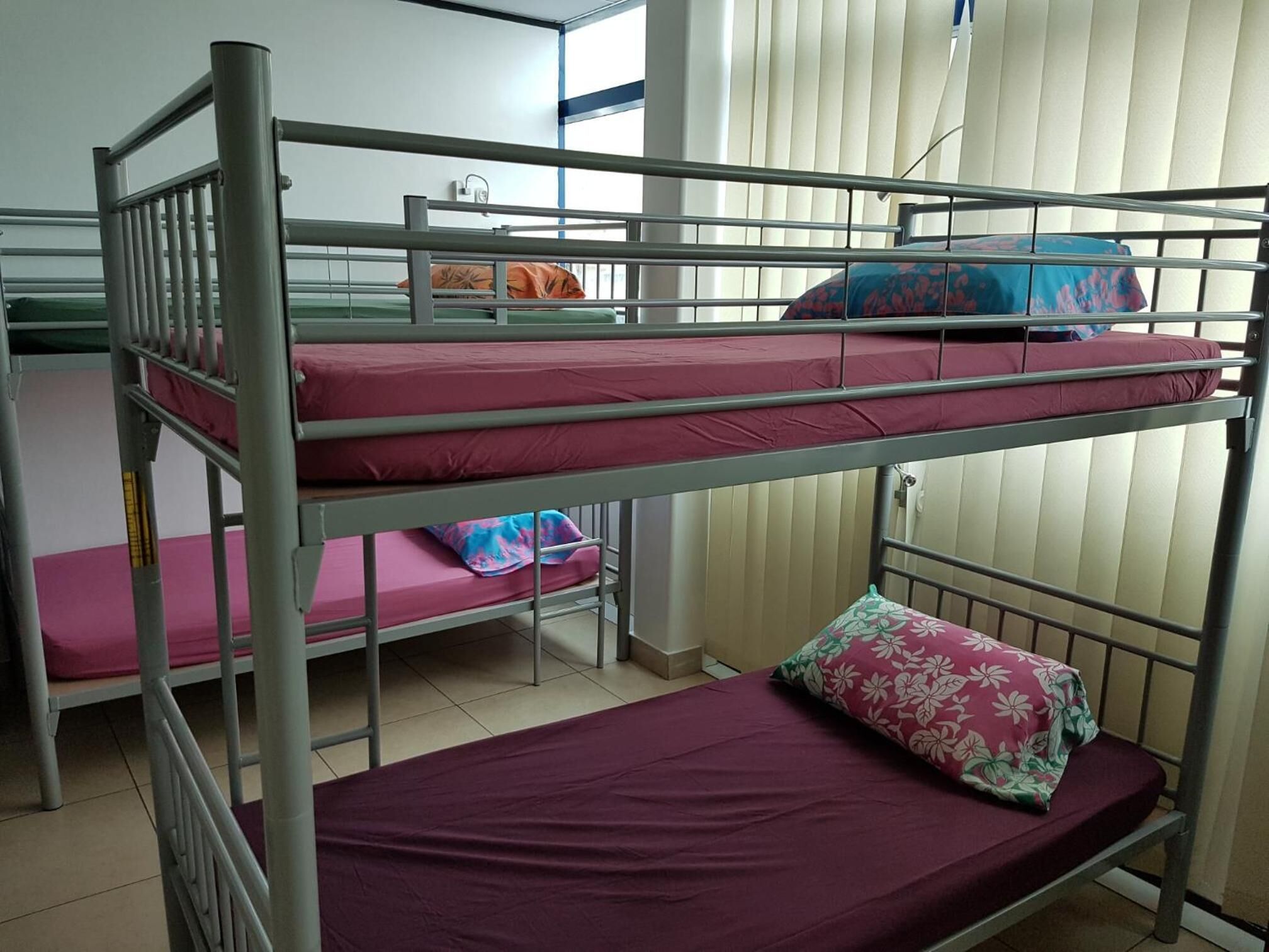 Habitación con literas escalonadas en tres niveles, cada una con colchón y almohadas.