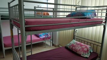 Habitación con literas escalonadas en tres niveles, cada una con colchón y almohadas.