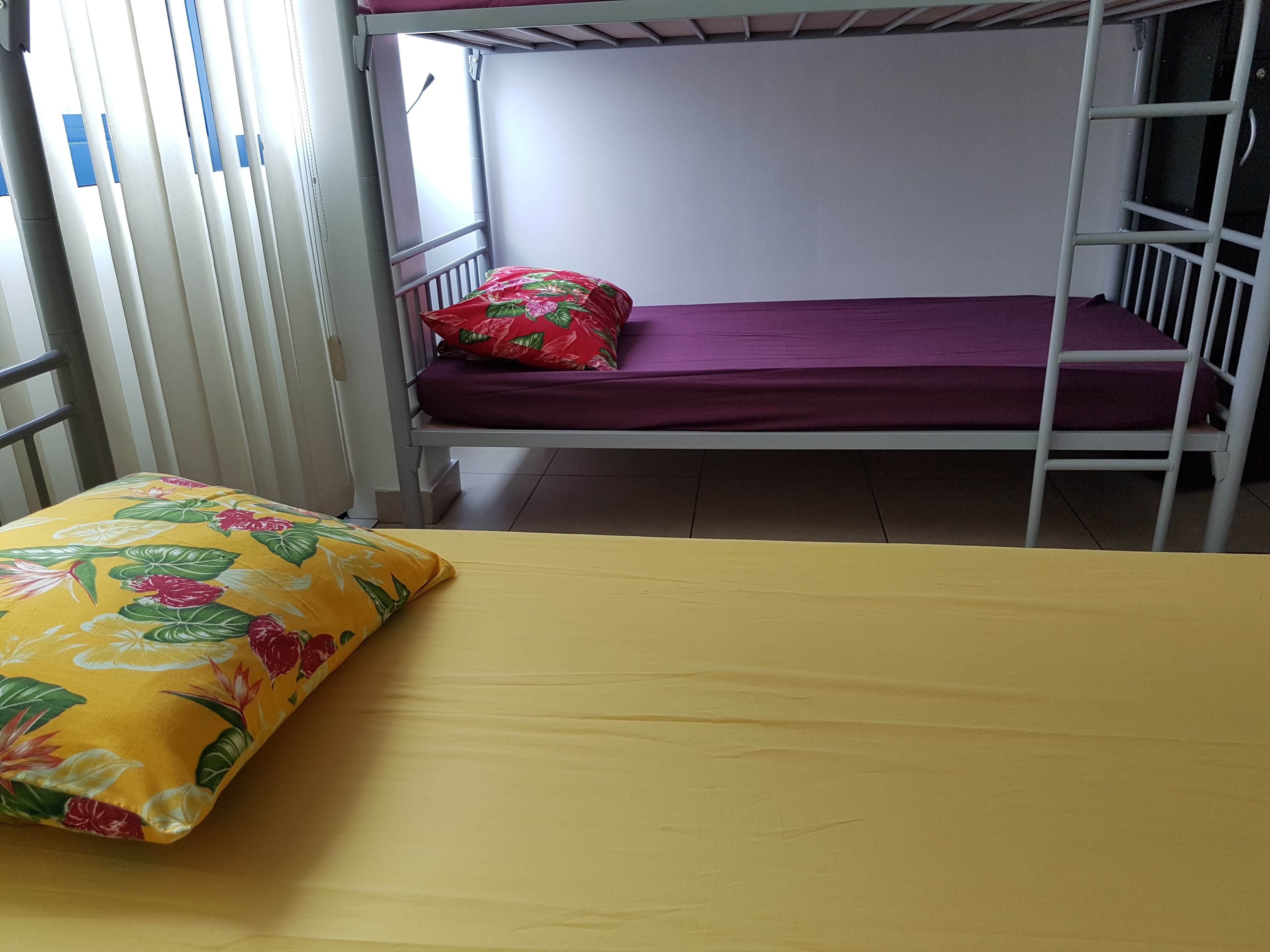 A bunk bed with a purple mattress and a floral pillow on the lower bunk.