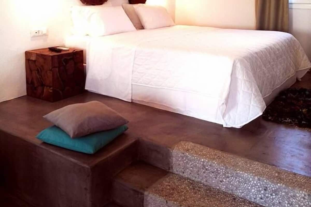 Un dormitorio con cama, mesita de noche, un adorno en la pared y una escalera.