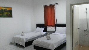 A hotel room with two single beds, a shower, and a painting on the wall. - De Ritz Hotel (Surabaya)